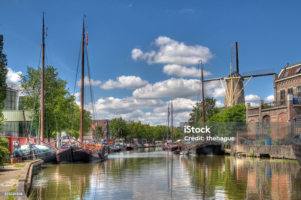 Canal in Gouda, Holland Windmill and historical boats in a canal in Gouda, Holland Gouda - South Holland Stock Photo