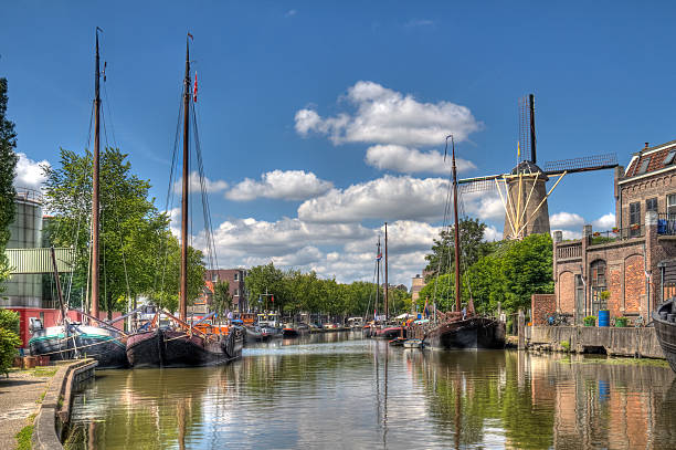 Canal in Gouda, Holland Windmill and historical boats in a canal in Gouda, Holland gouda south holland stock pictures, royalty-free photos & images
