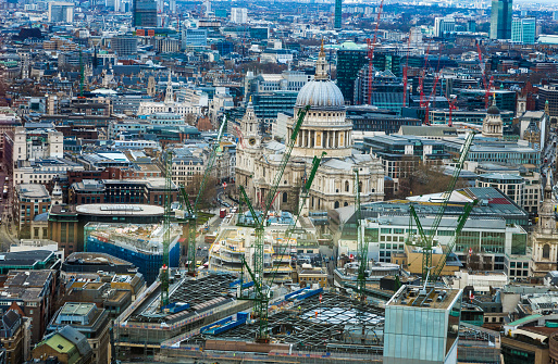 Aerial view view of the urban sprawl and growth of the London skyline, including the famous dome of St Paul's cathedral. This overhead shot shows the mass development and construction that is happening in the capital of the UK, with a multitude of cranes surrounding Sir Christopher Wren's famous dome. Horizontal colour image. 