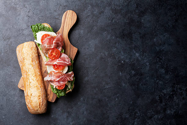 Ciabatta sandwich Ciabatta sandwich with romaine salad, prosciutto and mozzarella cheese on stone table. Top view with copy space prosciutto stock pictures, royalty-free photos & images
