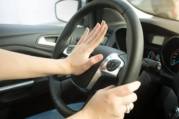 Photo of Closeup of annoyed woman driving car and honking