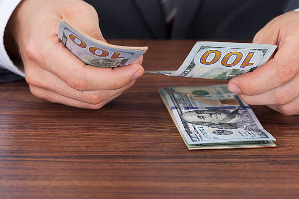 istock Businessman Counting Hundred Dollar Bills At Desk 525245021