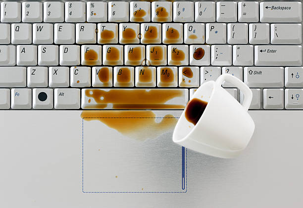 Coffee spilled on keyboard, Coffee spilled on keyboard, close up shot. Damaged computer that needs reparation. Data safety and laptop insurance concept. spilling stock pictures, royalty-free photos & images