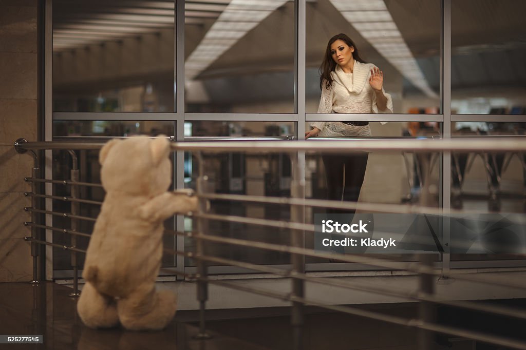 Girl says goodbye with a teddy bear. Sad girl waving, she says goodbye with a teddy bear and it's very sad. Adult Stock Photo