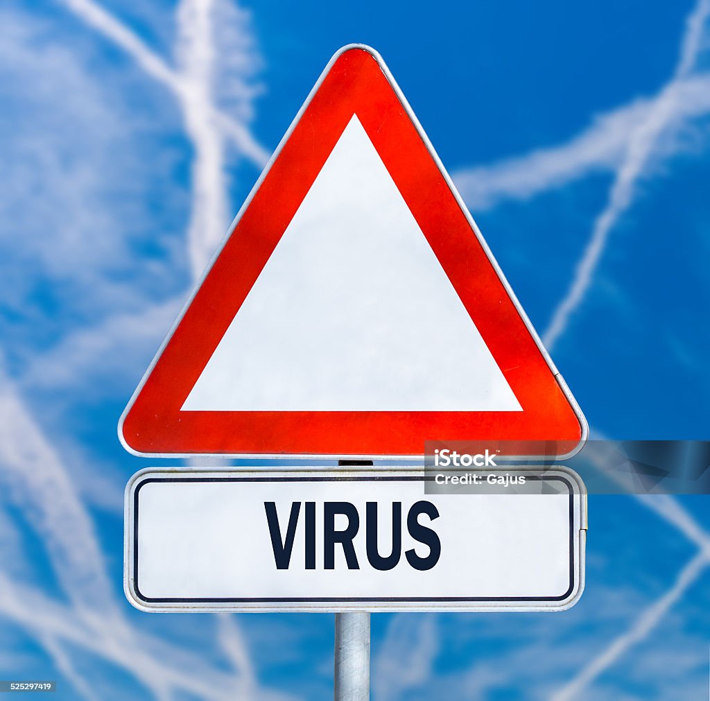 Traffic warning sign with the word - Virus Triangular red and white traffic warning sign with the word - Virus - against a blue sky criss-crossed with contrails from aircraft in a conceptual healthcare image. Alertness Stock Photo