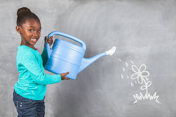 Girl watering her plant which is drawn on a blackboard stock photo