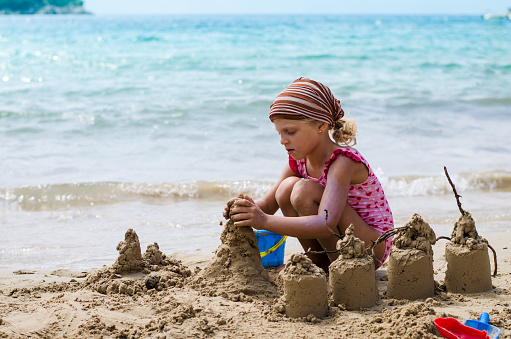 girl playing with sand in the beach