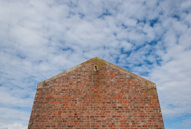 Facade of an house without windows made of red bricks. Sky with clouds in the background
