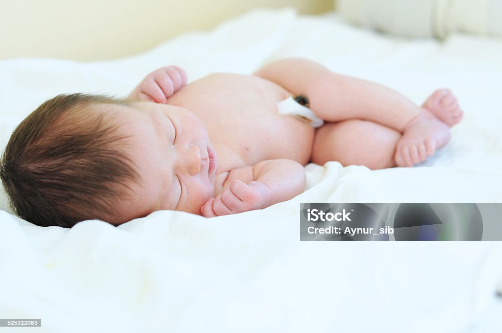 Newborn baby with umbilical cord sleeping undressed Newborn baby with umbilical cord sleeping on his first day in life undressed Asian and Indian Ethnicities Stock Photo