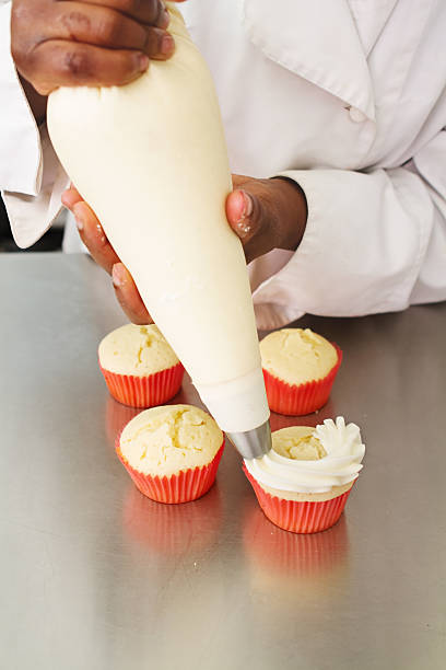 istock Pastry chef applying frosting to cupcakes 525326675