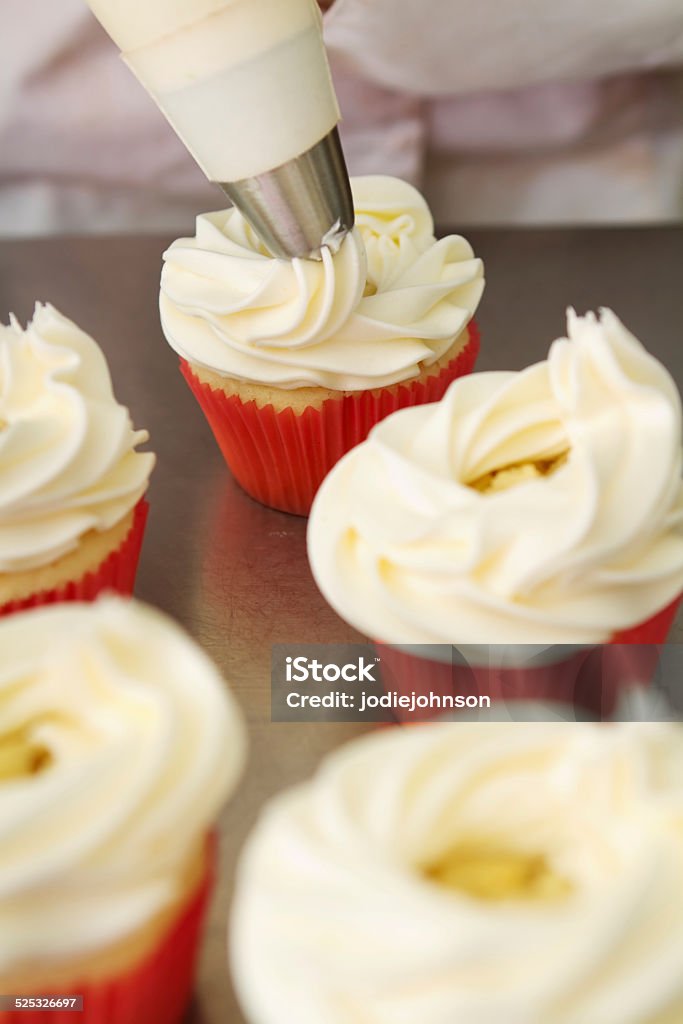 Whipped butter cream frosting applied to cupcakes Whipped butter cream frosting applied to vanilla cupcakes Baked Pastry Item Stock Photo