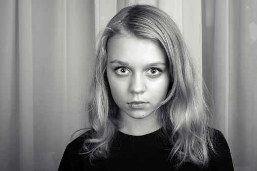 Serious blond Caucasian girl, monochrome studio portrait