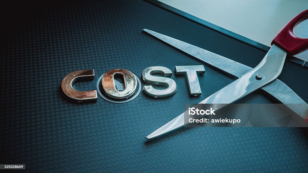 Stainless steel scissor next to word cost. Concept of cost-cutting Cutting Costs Stock Photo