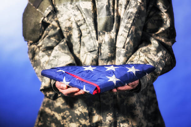 istock Military Soldier Presenting USA Flag Folded 525331969