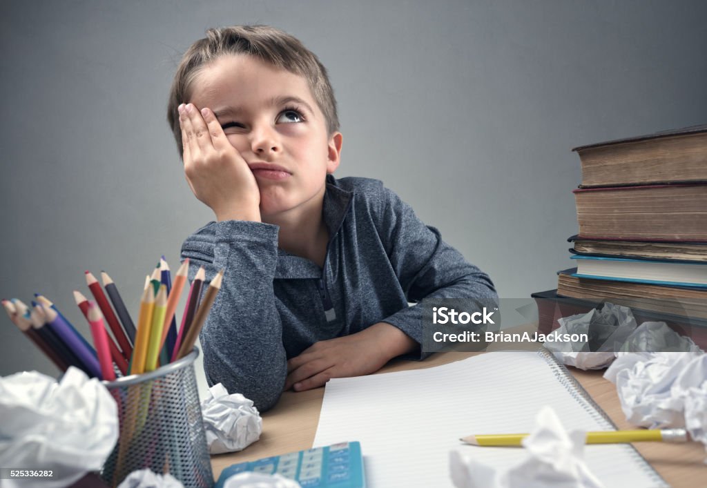 Bored and fed boy up doing his homework Thinking child bored, frustrated and fed up doing his homework Child Stock Photo