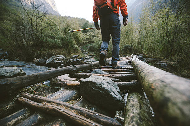 Trekking Cropped shot of mountain trekker crossing the bridge in region of Annapurna, Himalayas. raining outside stock pictures, royalty-free photos & images
