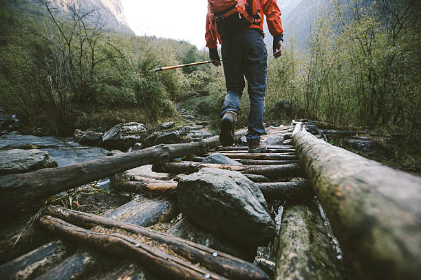 Trekking Cropped shot of mountain trekker crossing the bridge in region of Annapurna, Himalayas. outdoor pursuit stock pictures, royalty-free photos & images