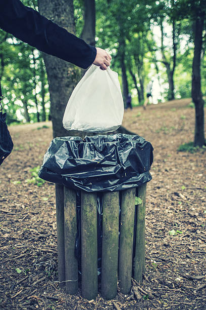 istock Hand of woman throwing garbage into bin in a park 525336632