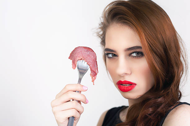istock woman holding fork with piece of meat 525339586