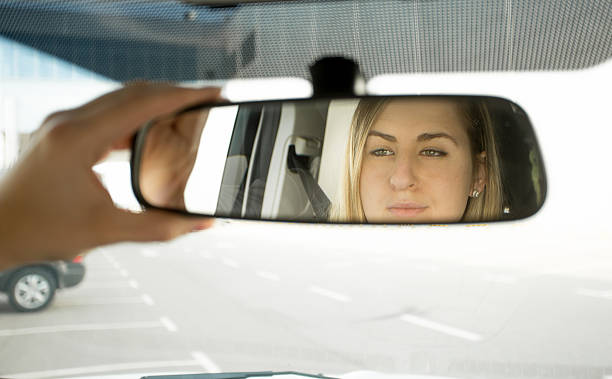 istock woman adjusting car mirror and looking in the reflection 525341244