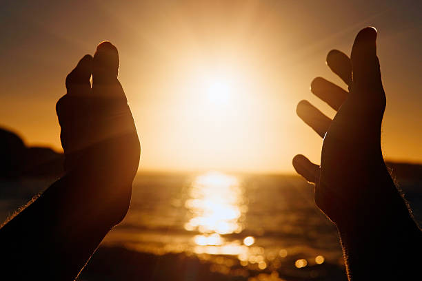 Silhouetted hands stretched out to the setting sun Hands seen in silhouette outstretched towards the setting sun. Copy space on the sun and sky. tonatiuh stock pictures, royalty-free photos & images