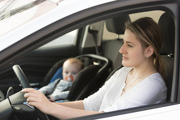 istock Mother driving car with her baby sitting on front seat 525346472