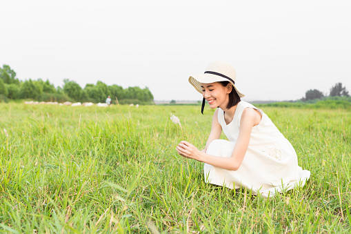 chinese girl with a straw hat, a man sitting on green grassland and enjoy the good times