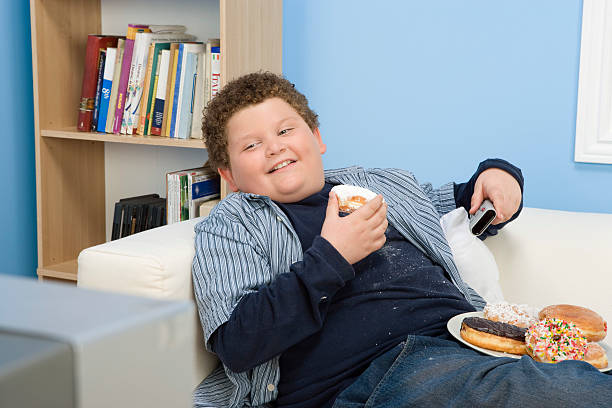 Overweight Child Boy Eating Donuts overweight boy stock pictures, royalty-free photos & images