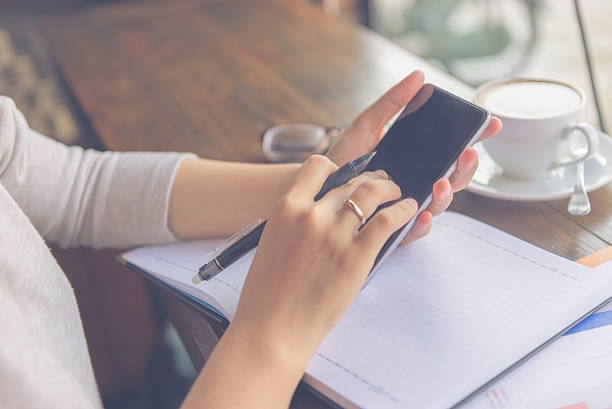 istock Married woman hand holding pen while tapping smartphone screen 525353140