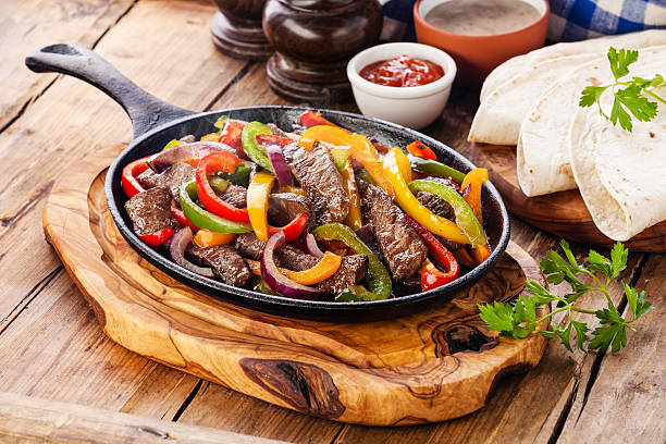 Beef Fajitas Beef Fajitas with colorful bell peppers in pan and tortilla bread and sauces beef stock pictures, royalty-free photos & images