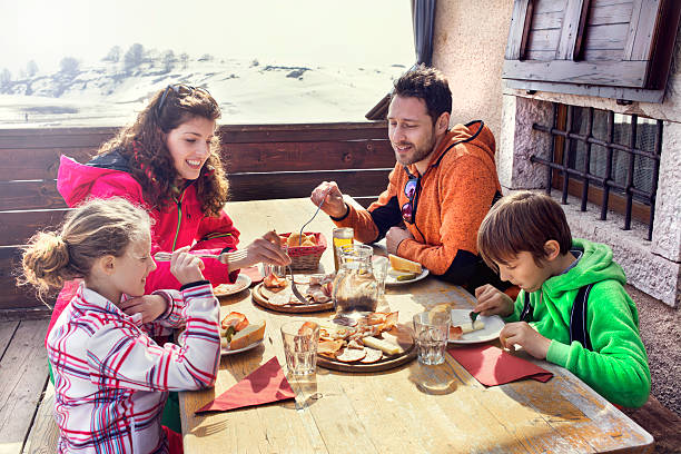 famiglia avendo pranzo in uno chalet in montagna - hut winter snow mountain foto e immagini stock