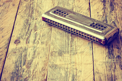 vintage harmonica lying on wooden table, retro toned effect