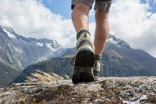 Man's legs and hiking boots standing on rocky peak. Shot on the Key summit track in New Zealand.