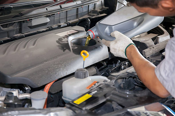 istock Servicing mechanic pouring new oil lubricant into the car engine 525363094