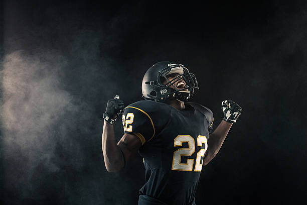 Competition Young African American football player with his hands up yelling. american football sport stock pictures, royalty-free photos & images