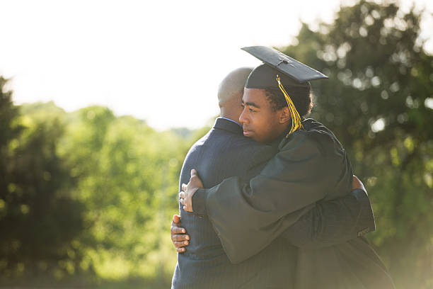 african american padre e hijo en el día de la graduación - poses para fotos de graduación fotografías e imágenes de stock