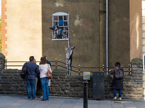 Bristol, UK - November 1, 2014: Viewed from Park Street, Naked Man - is an original example of Banksy grafitti artwork in Bristol which itself has been defaced by a paint bomb attack. It still attracts the attention of many visitors to Bristol.