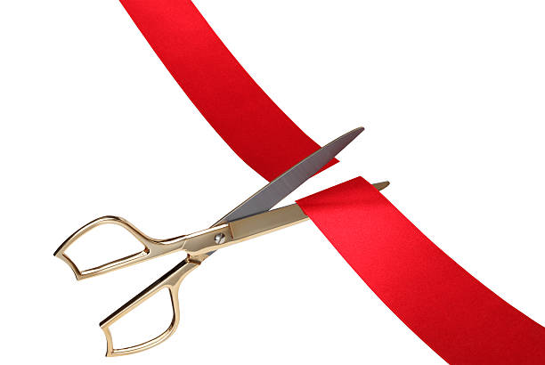 Red Ribbon Cutting Ceremony Closeup image of scissors cutting a red ribbon. gold scissors stock pictures, royalty-free photos & images