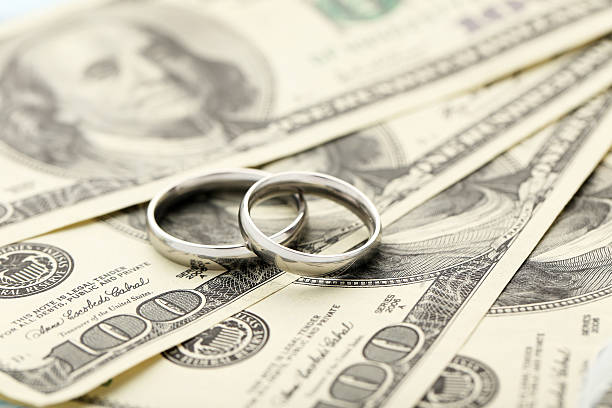 istock Silver wedding rings on one hundred dollars bill background 525365870