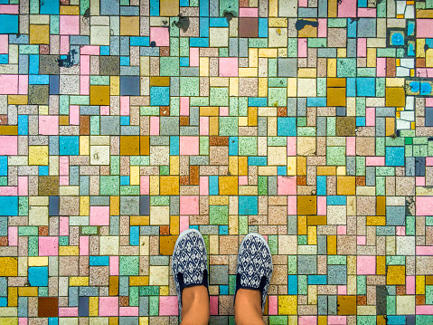 Colorful pavers and foots, brick road and feet in sandals, travel in Asia, colorful way, first step on road, city decoration, colorful floor, bright tiles, vintage ornament on the street, street life