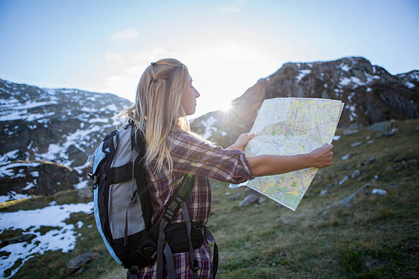 istock Female tourist lost in mountain tracks,looking at map 525371309