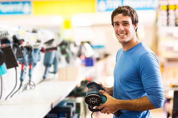 young man purchasing hand tool in hardware shop stock photo