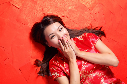 happy chinese new year. Smile woman lying on red envelope bed, high angle view