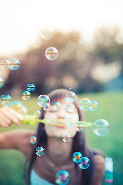istock beautiful young woman with white dress blowing bubble 525378949