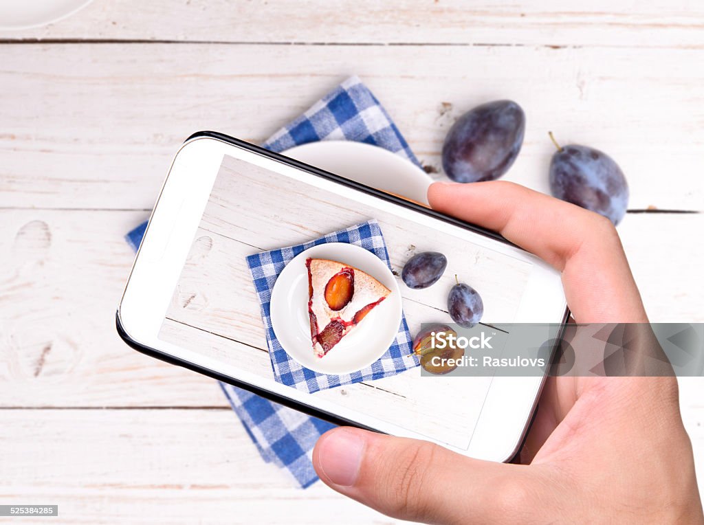 Hands taking photo plum cake with smartphone Hands taking photo plum cake with smartphone.  Baking Stock Photo