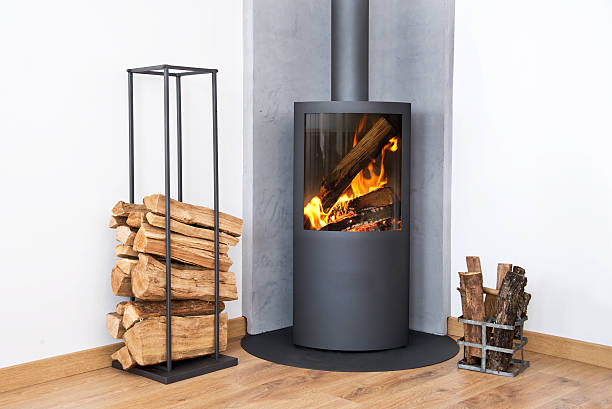 Modern burning stove next to a wood logs rack Modern burning stove next to a wood logs rack. wood burning stove stock pictures, royalty-free photos & images