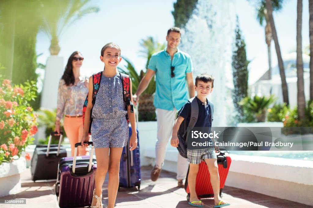 Family with suitcases passing by fountain in tourist resort  Family Stock Photo
