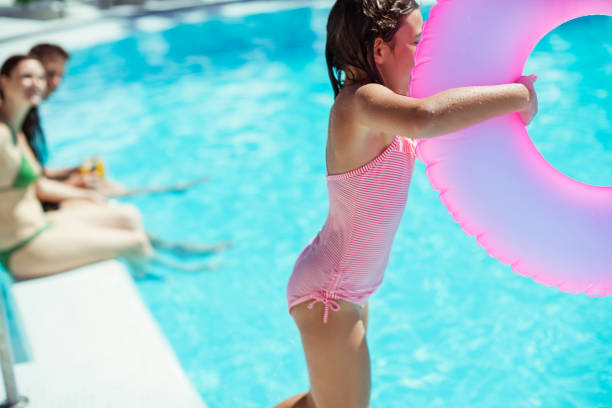 スイミングプールに飛び込むピンクのインフレータブルリングを持つ女の子 - men child swimming pool women ストックフォトと画像