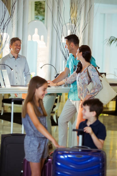 istock Family with suitcases talking with receptionist in hotel lobby 525409329