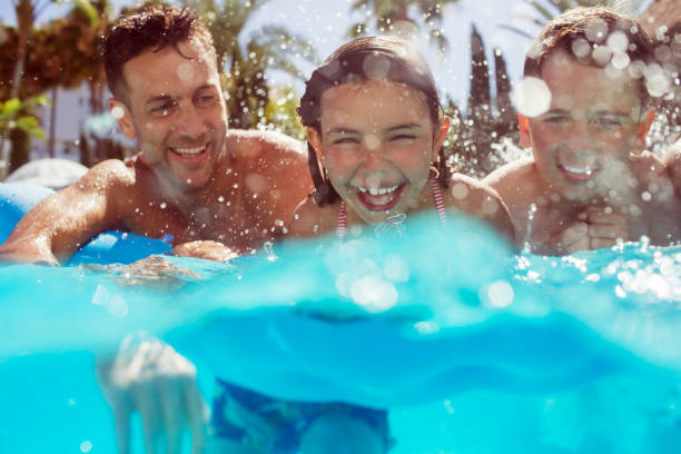 padre nadando con sus dos hijos en la piscina - albercas fotografías e imágenes de stock